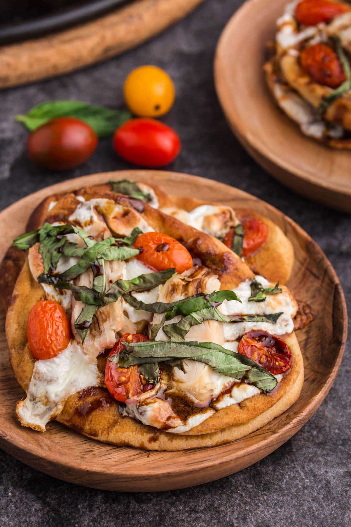 mini naan chicken caprese pizzas on a wooden plate