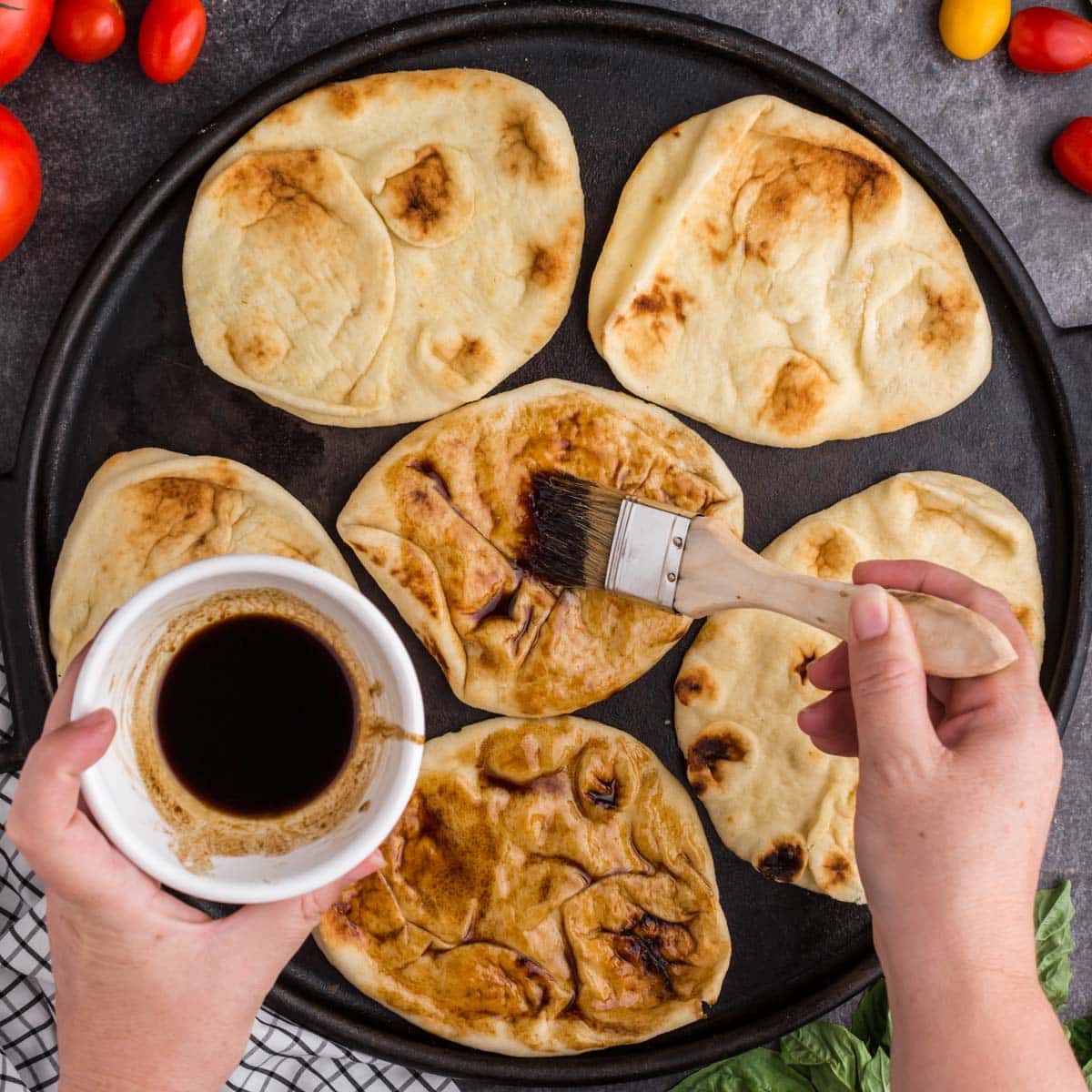 brushing balsamic glaze over naan