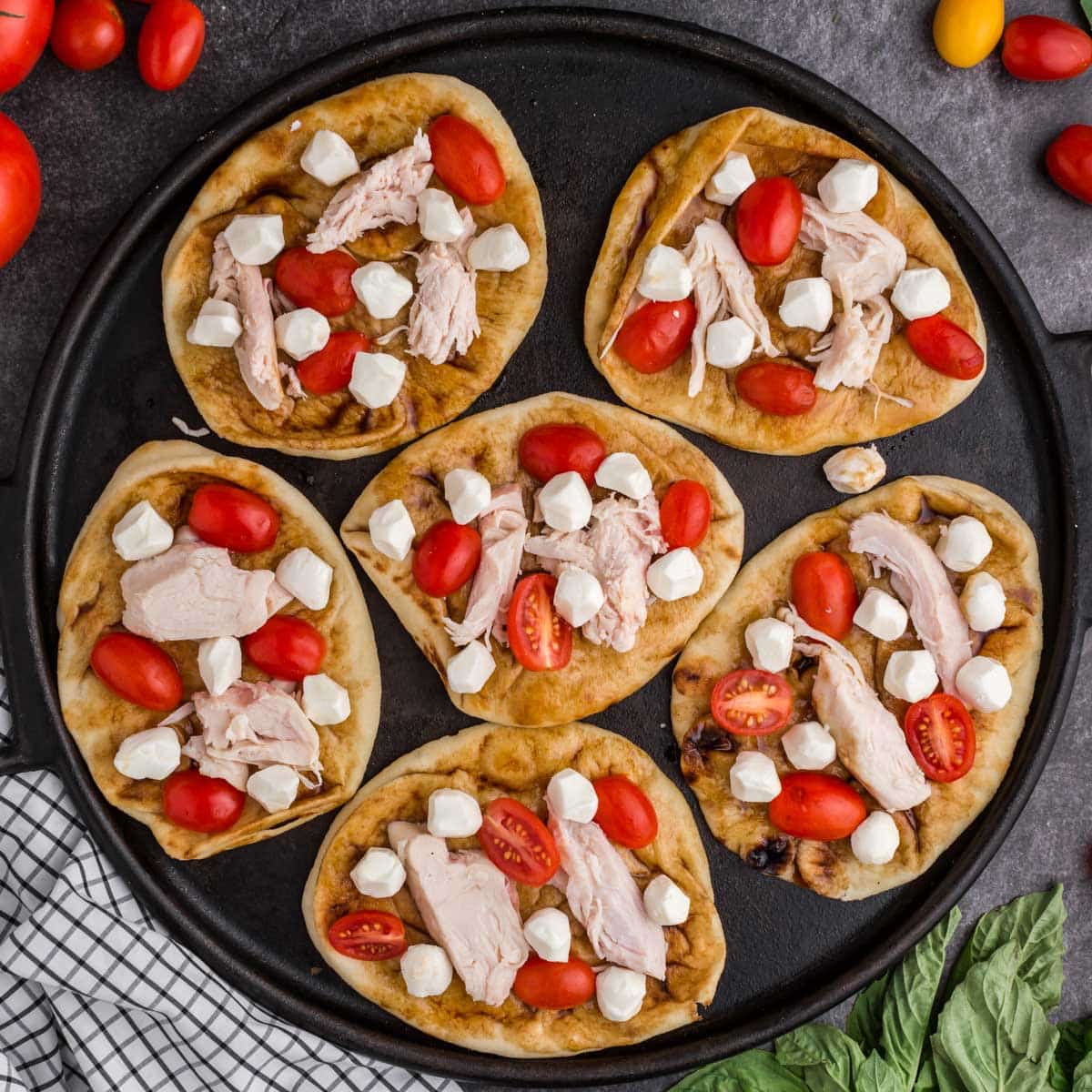 uncooked chicken caprese pizzas on a skillet