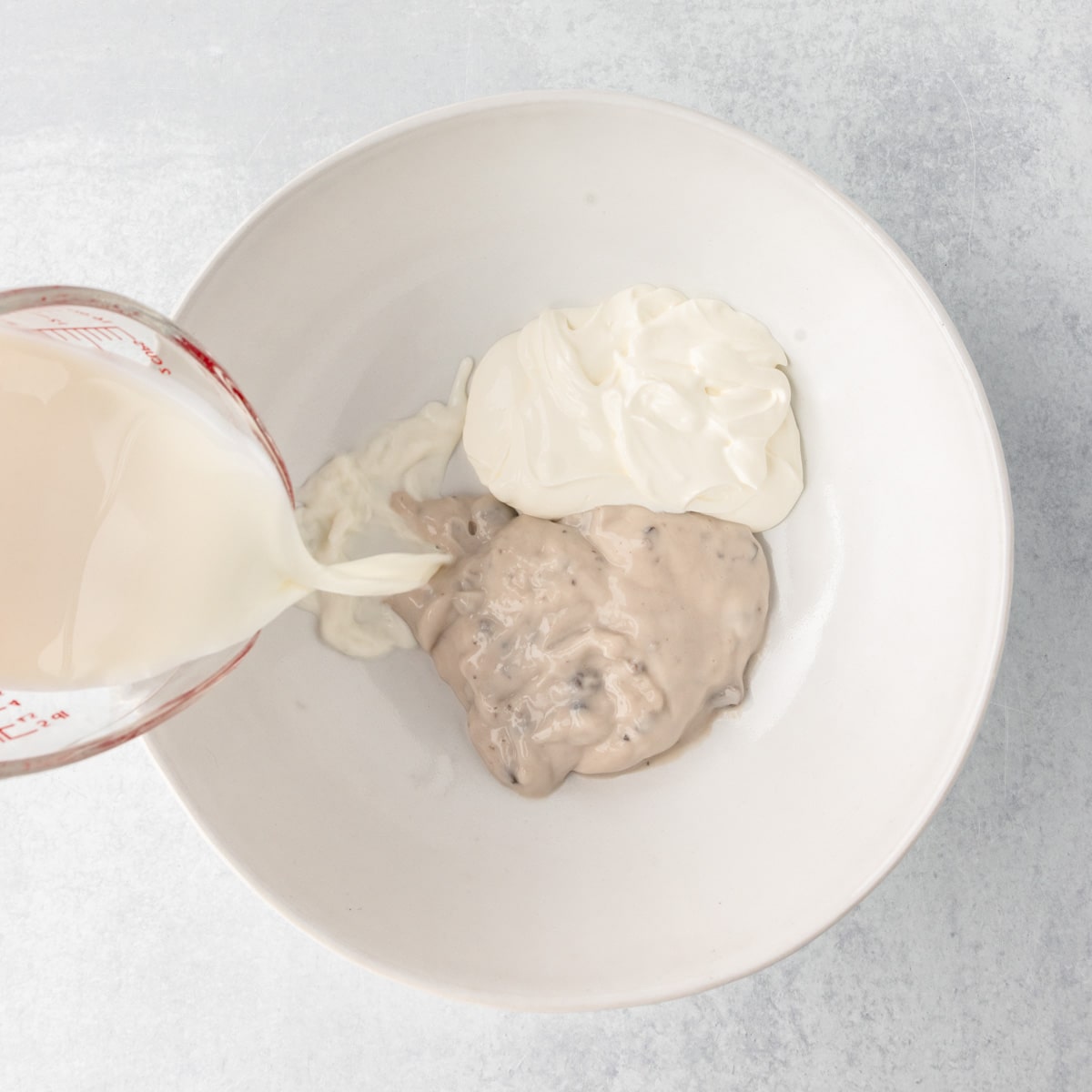 pouring milk over cream soups in a bowl