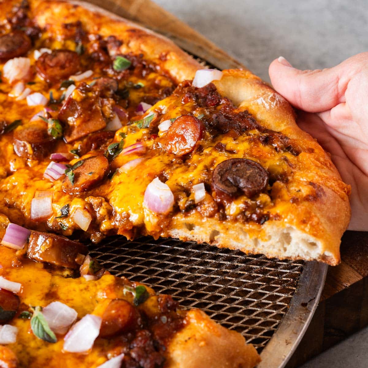 a hand holding a slice of chili pizza