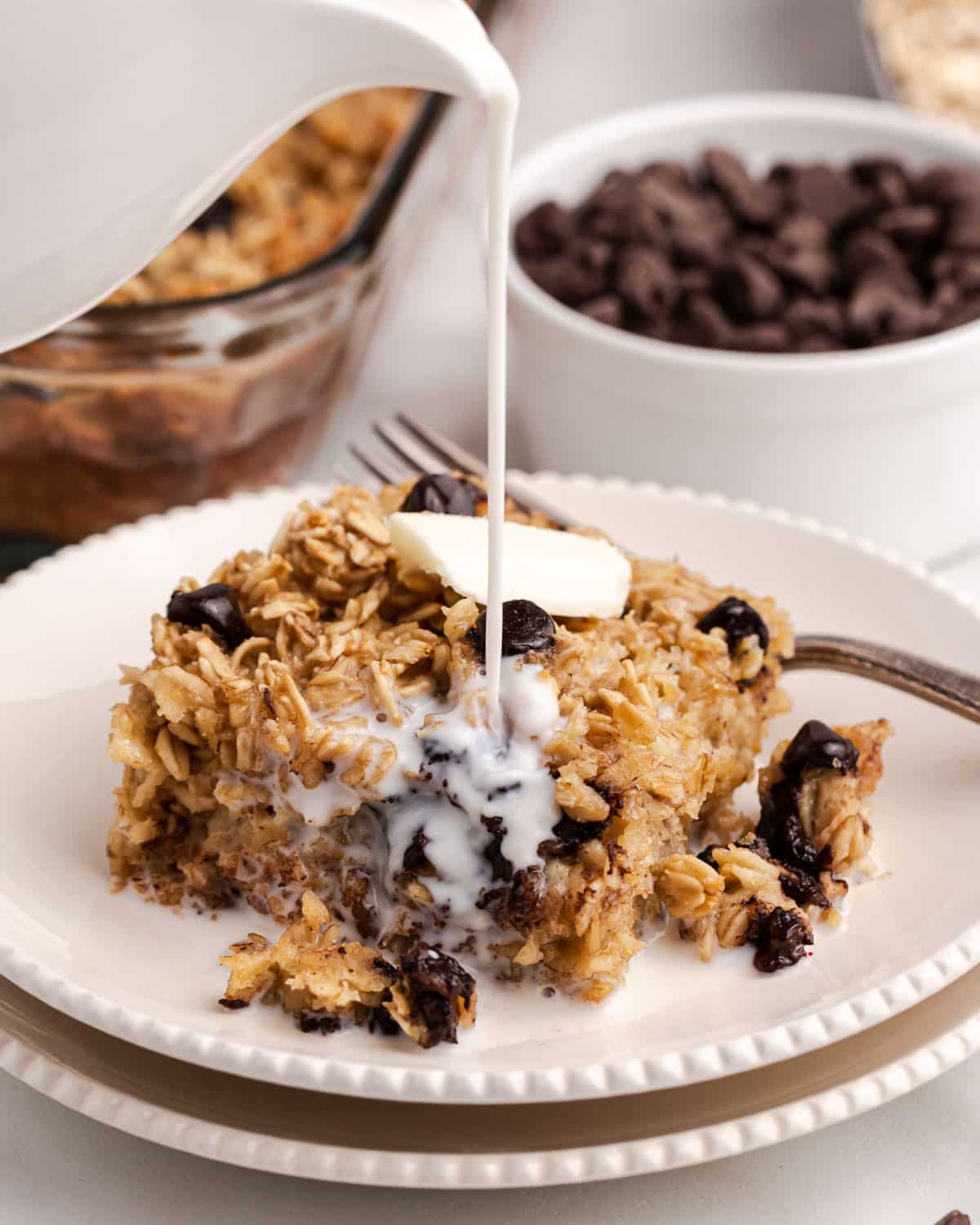 pouring milk over a piece of chocolate chip baked oatmeal