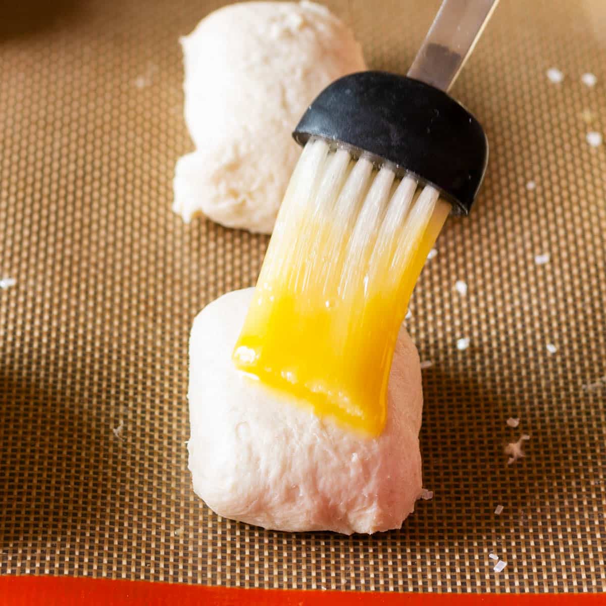 brushing egg wash over unbaked biscuits