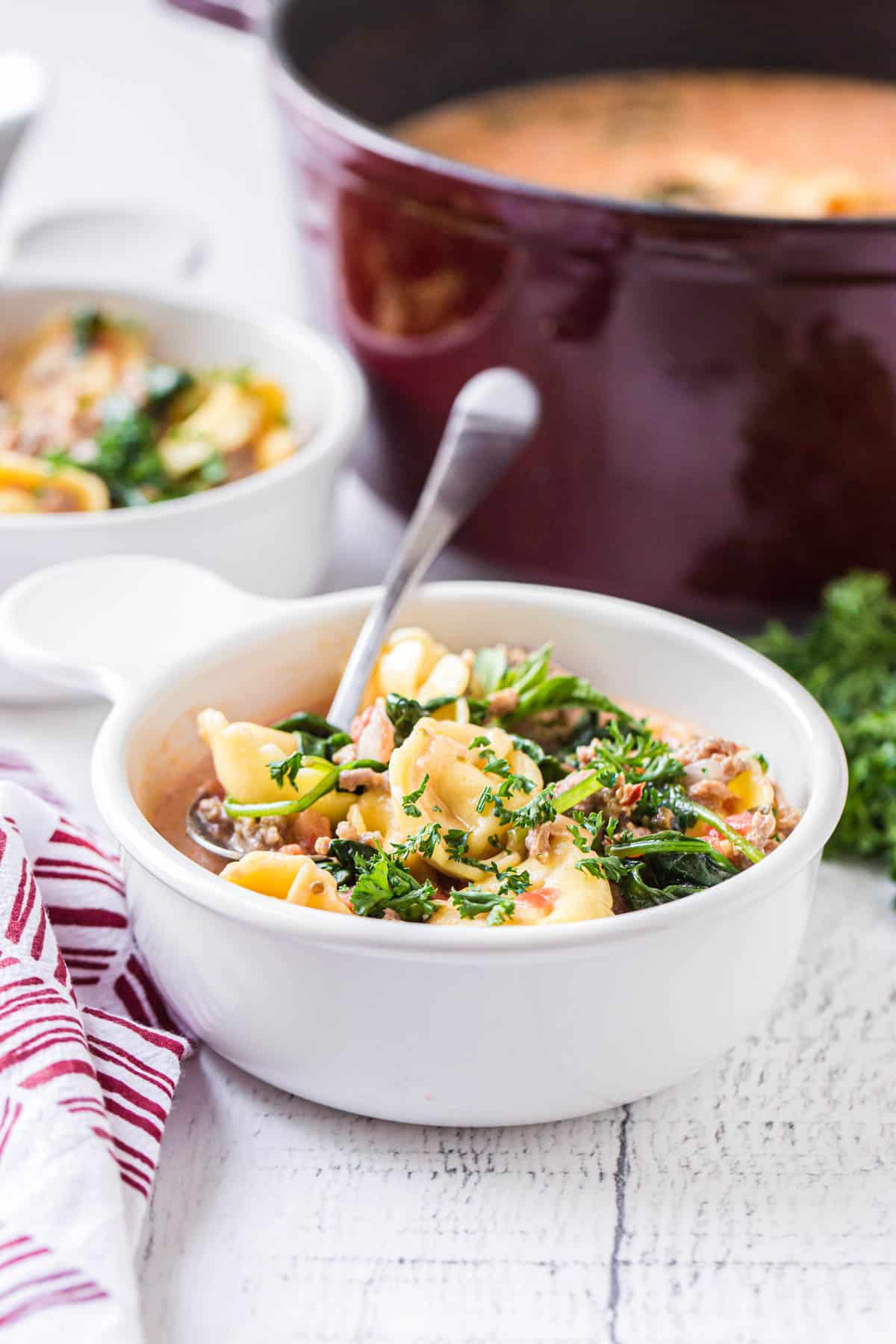 a bowl of soup on a table with a dutch oven in the background