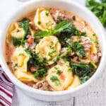 a bowl of tortellini soup with spinach