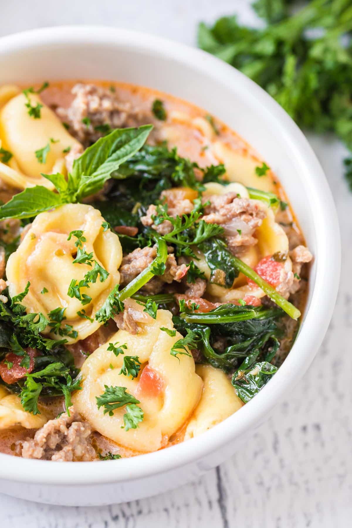 tortellini soup with spinach and sausage in a bowl