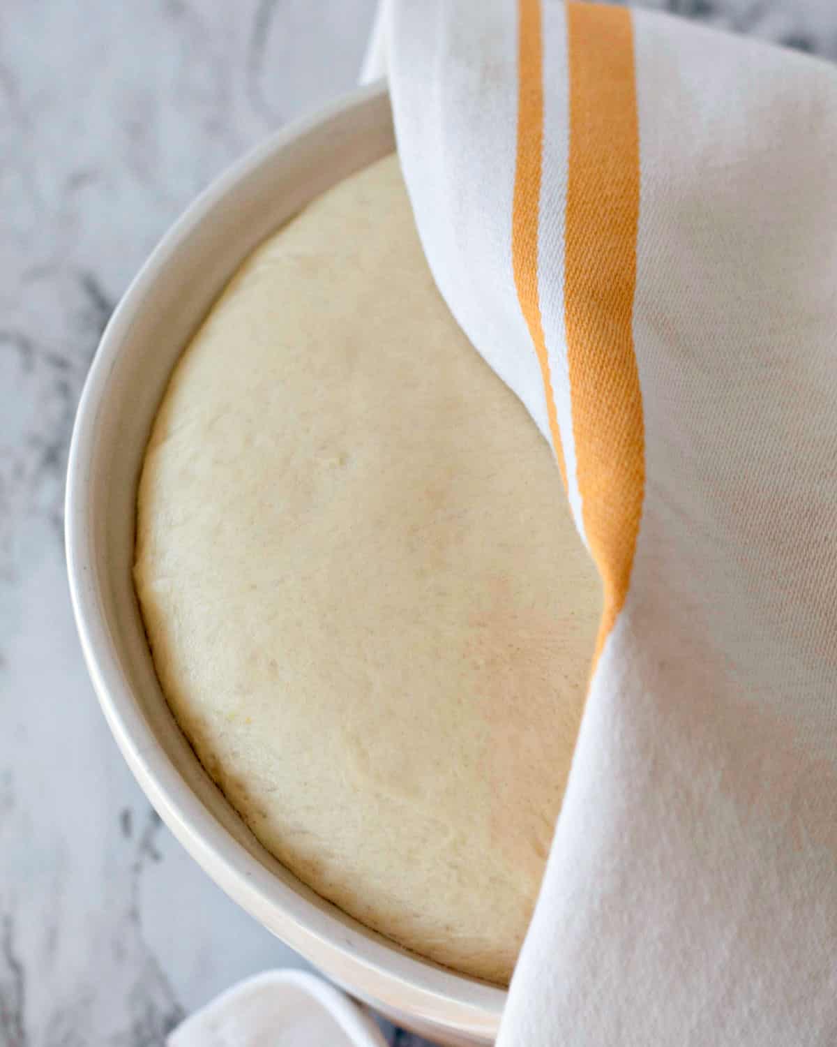 dough risen in a bowl, covered with a towel