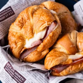 3 hot ham and cheese croissant sandwiches in a basket