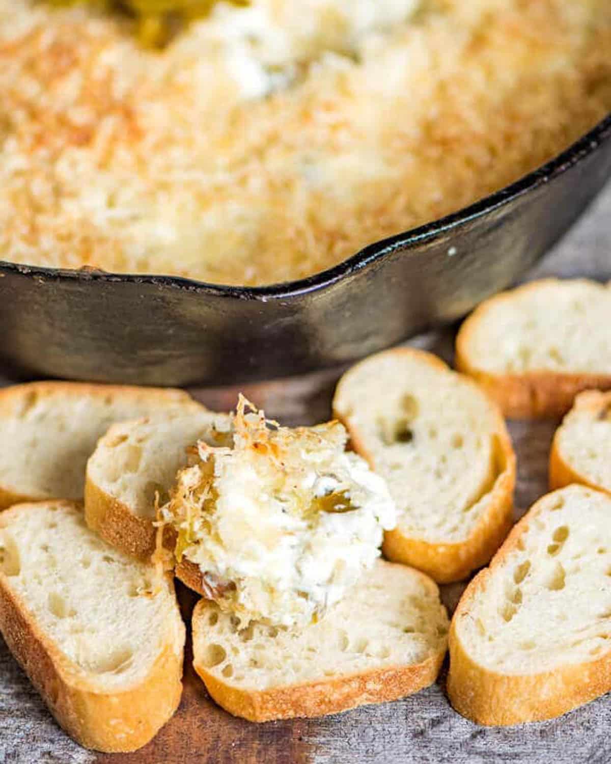 jalapeno popper dip in a cast iron skillet with slices of bread