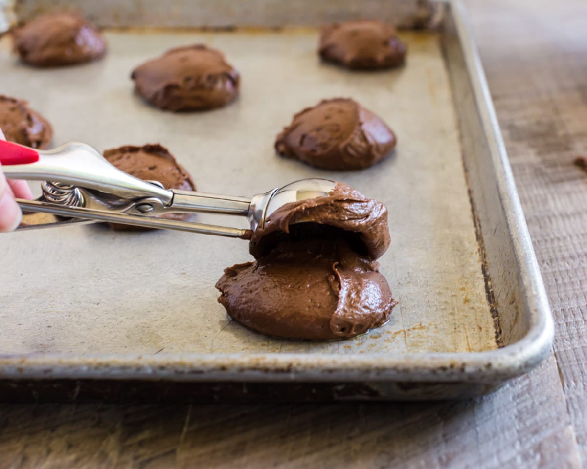 scooping chocolate batter onto a baking pan