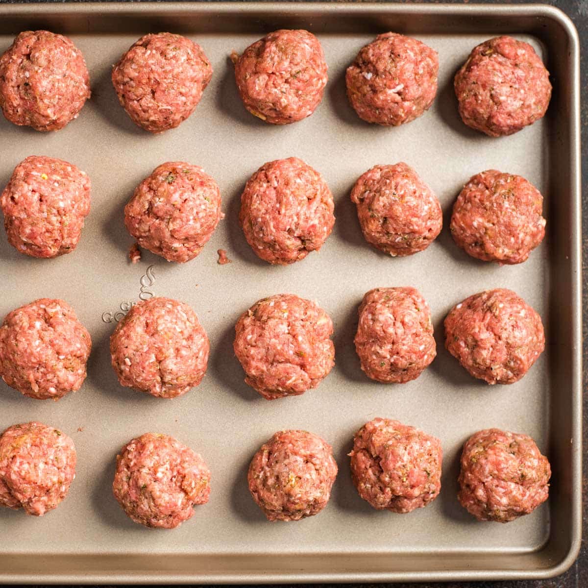 uncooked meatballs on a baking sheet