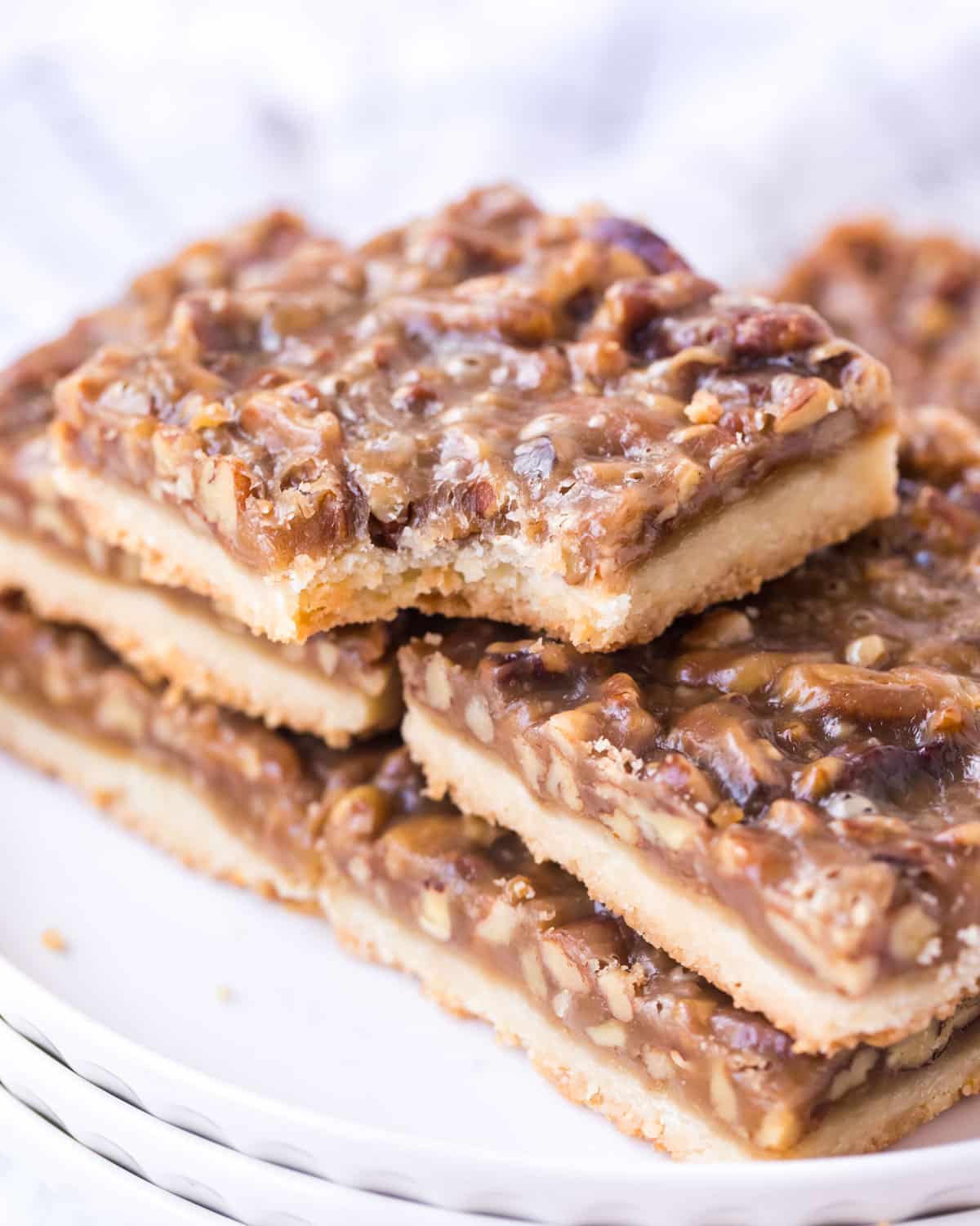 a stack of pecan pie bars on a plate, with one bite out