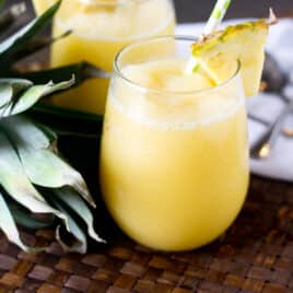 a glass of pineapple tropical smoothie with a straw