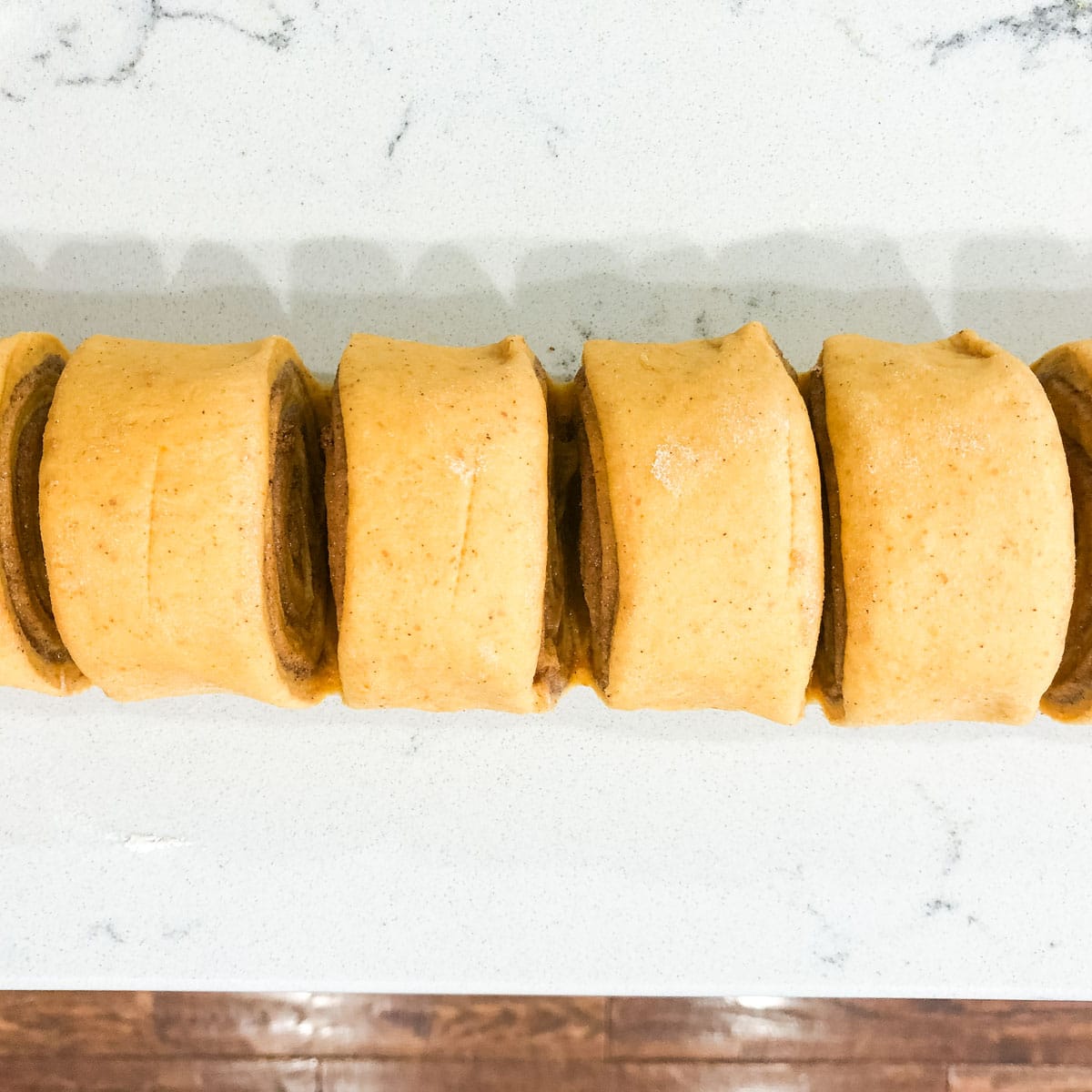 cut cinnamon roll dough on a table