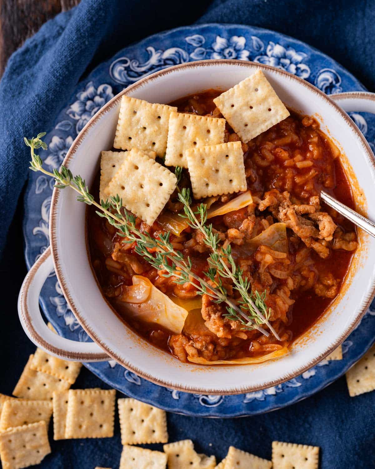 a bowl of stuffed cabbage soup with crackers and fresh thyme