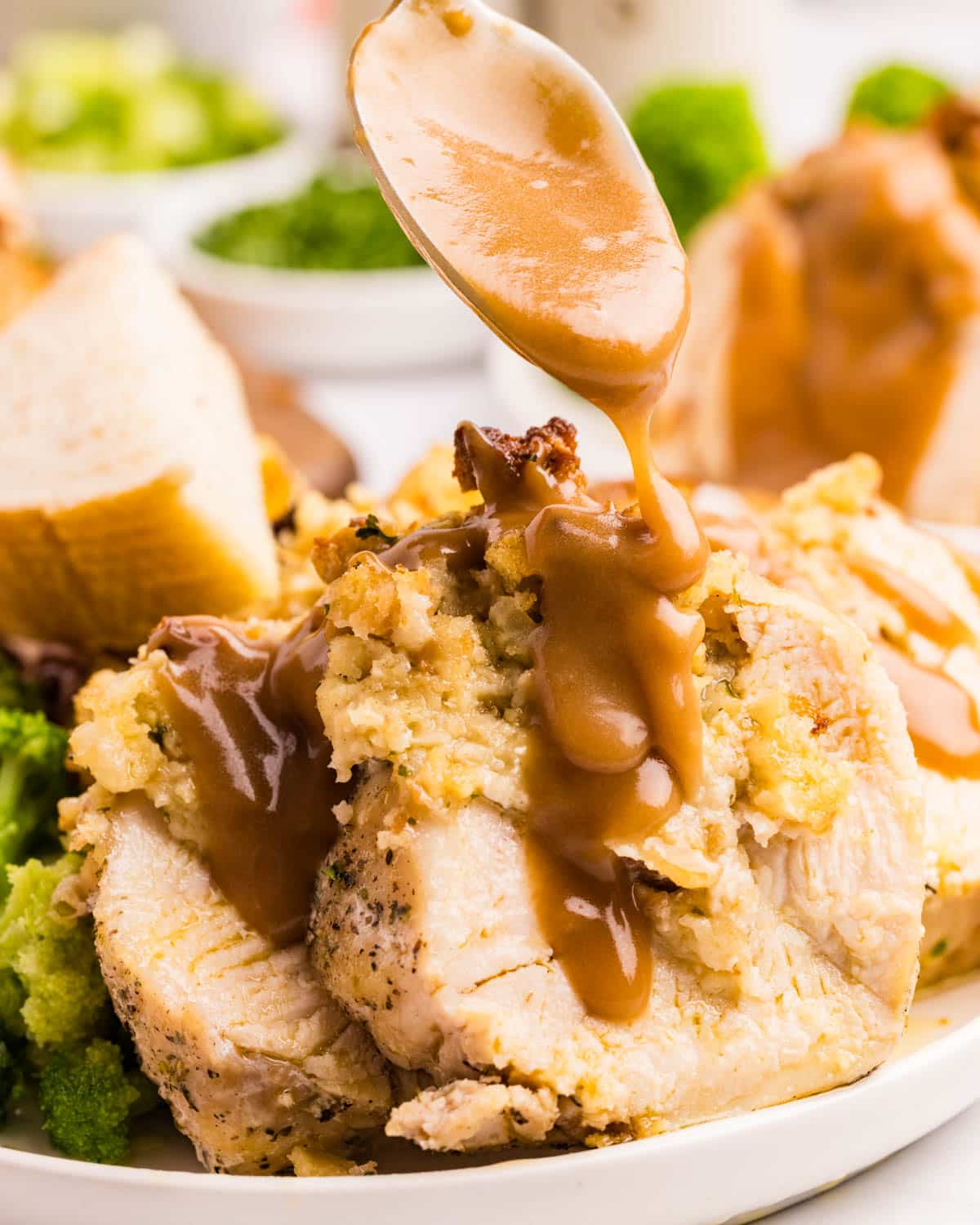 pouring gravy over a stuffed chicken breasts