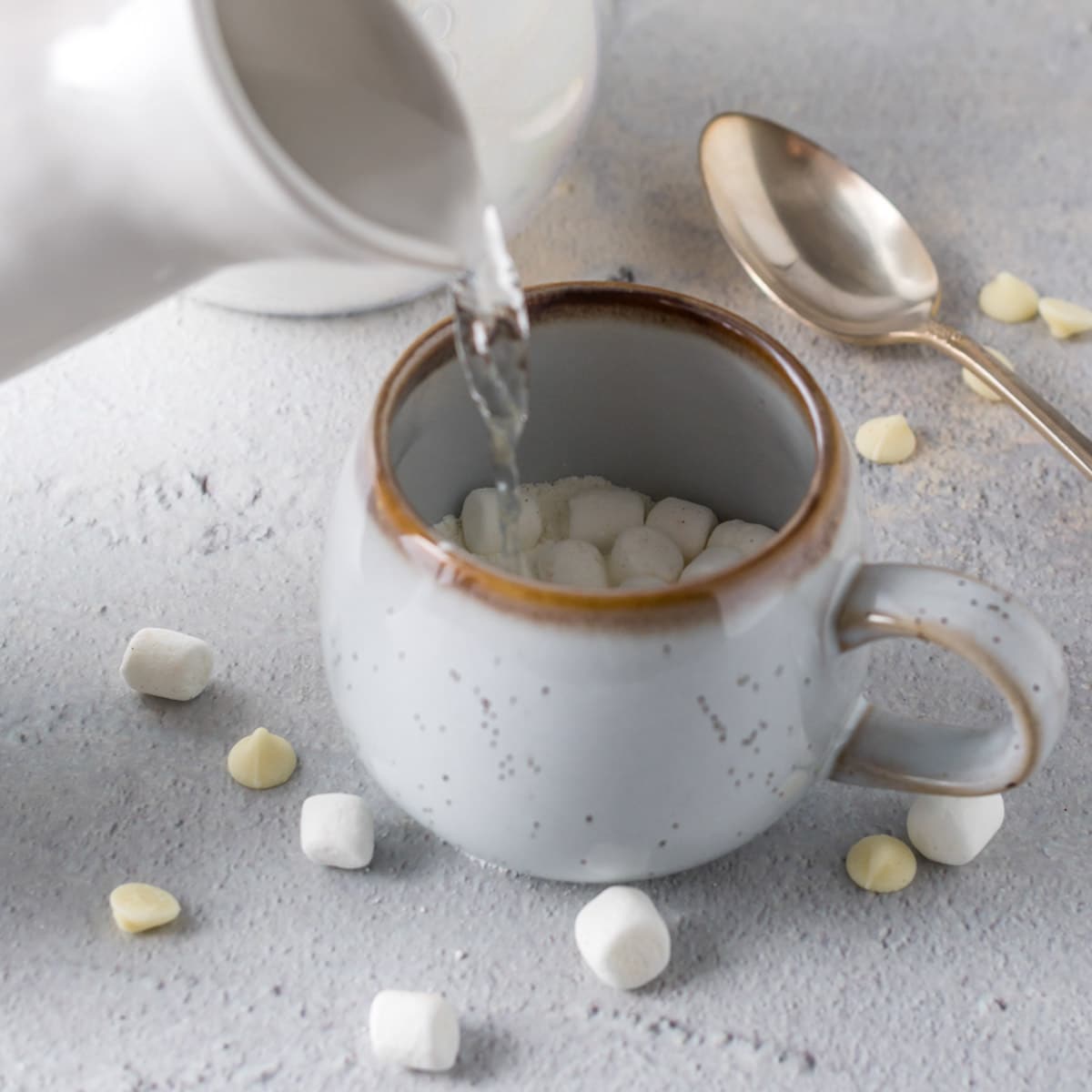 pouring hot water into a mug with white hot chocolate mix