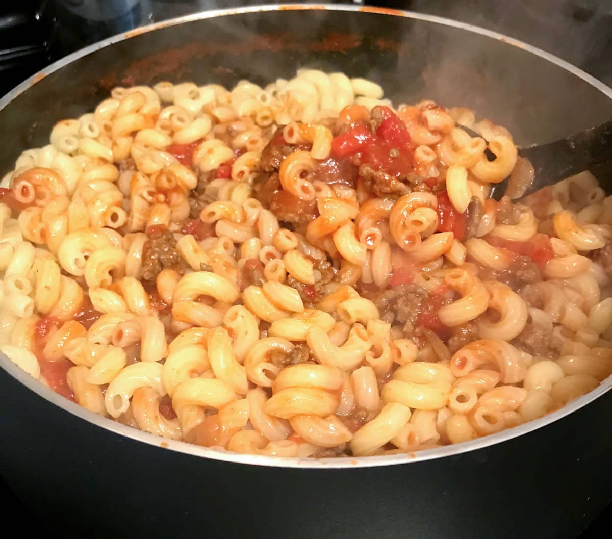 a skillet with macaroni noodles, ground beef and tomatoes