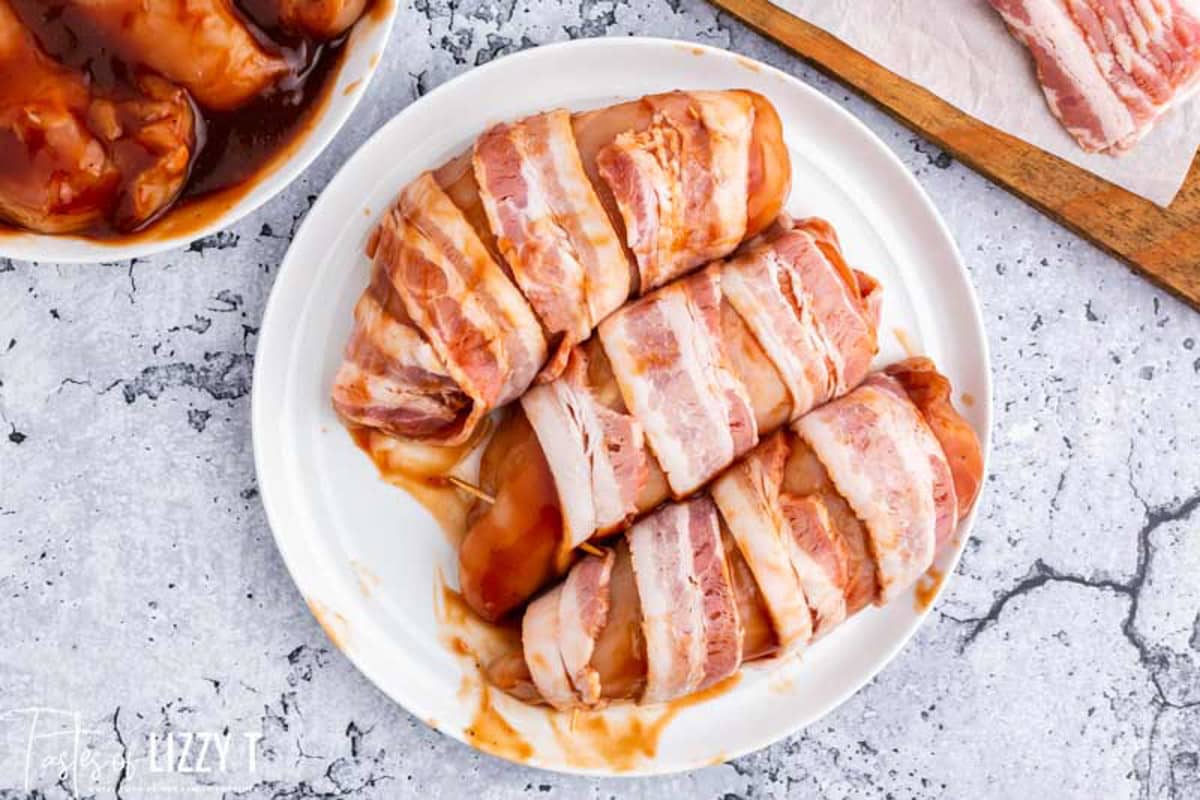 uncooked chicken wrapped with bacon on a plate