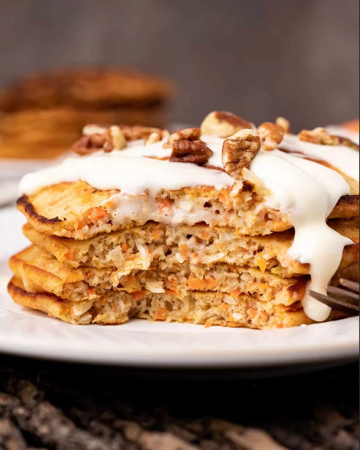 a stack of 4 carrot cake pancakes with vanilla glaze