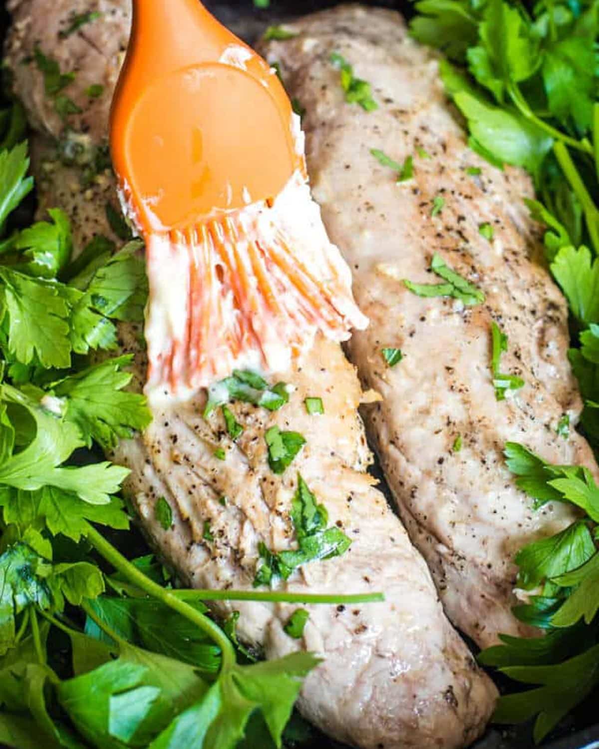 brushing garlic butter over pork tenderloin