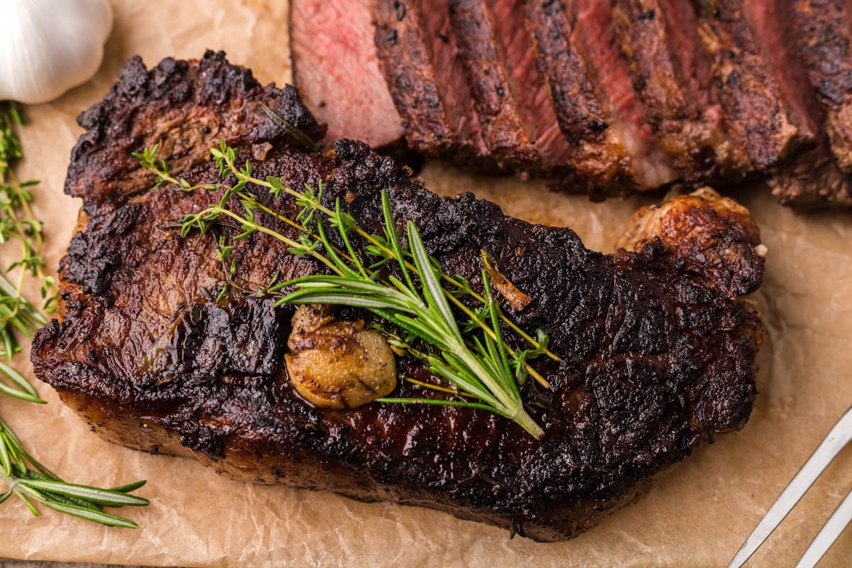 closeup of a steak with fresh thyme and rosemary