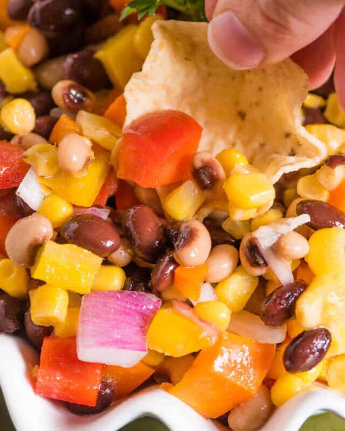 a tortilla scooping up a fresh corn and bean salsa