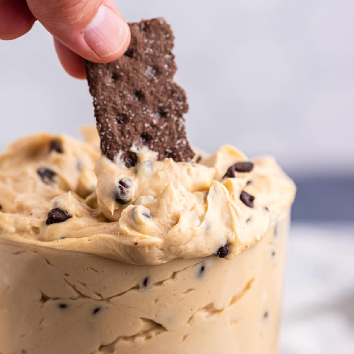 a graham cracker scooping into peanut butter cheesecake dip