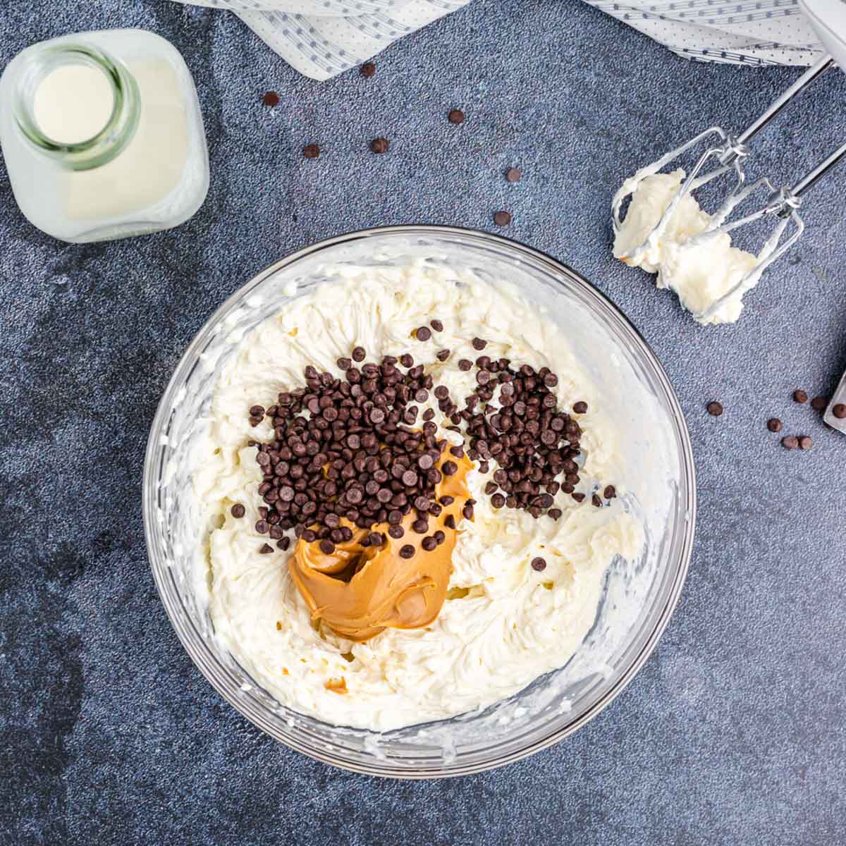 peanut butter and chocolate chips over cream cheese mixture in a bowl