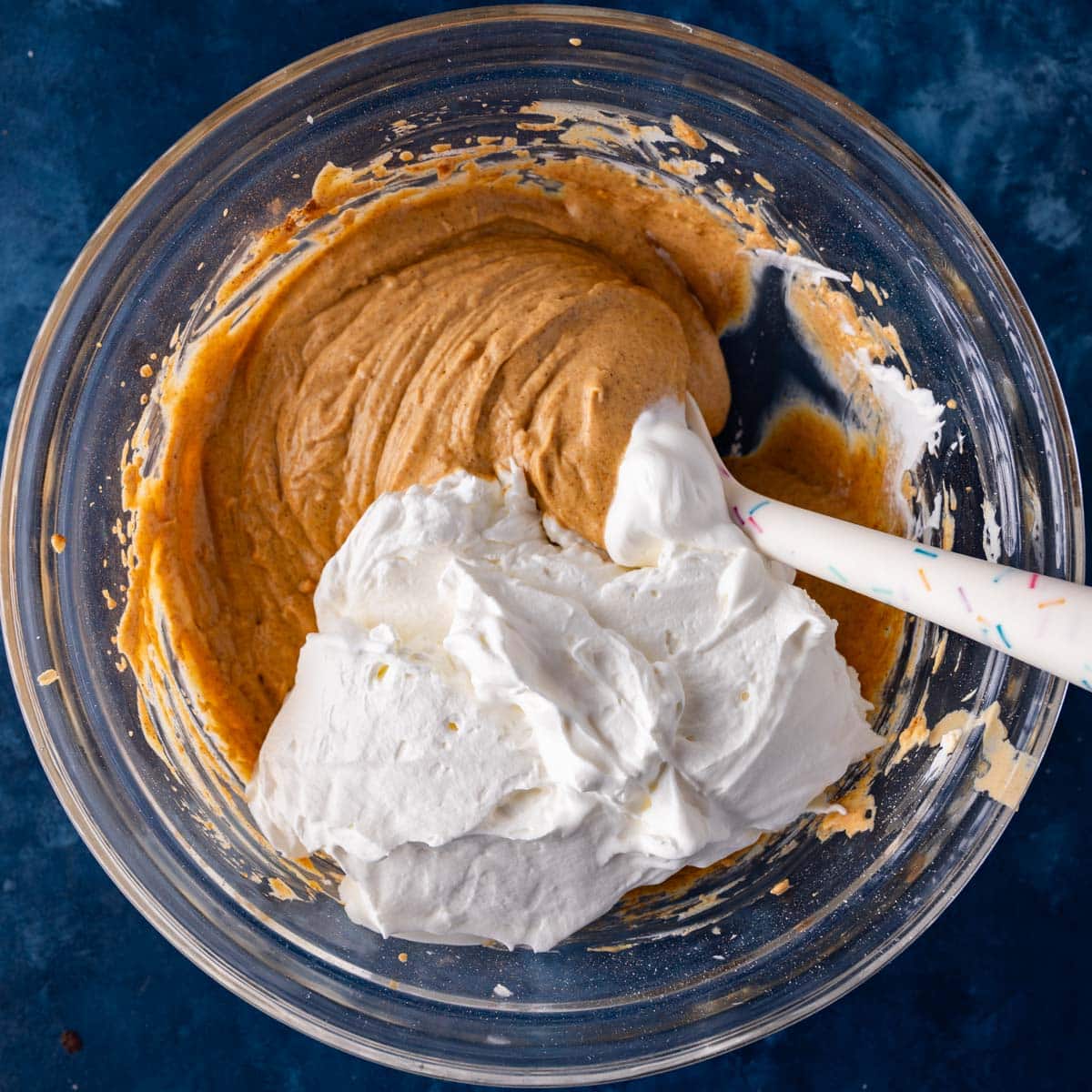 whipped cream over pumpkin mixture in a bowl