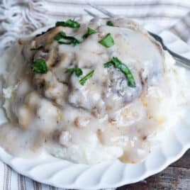 a plate of mashed potatoes with salisbury steak and mushroom gravy