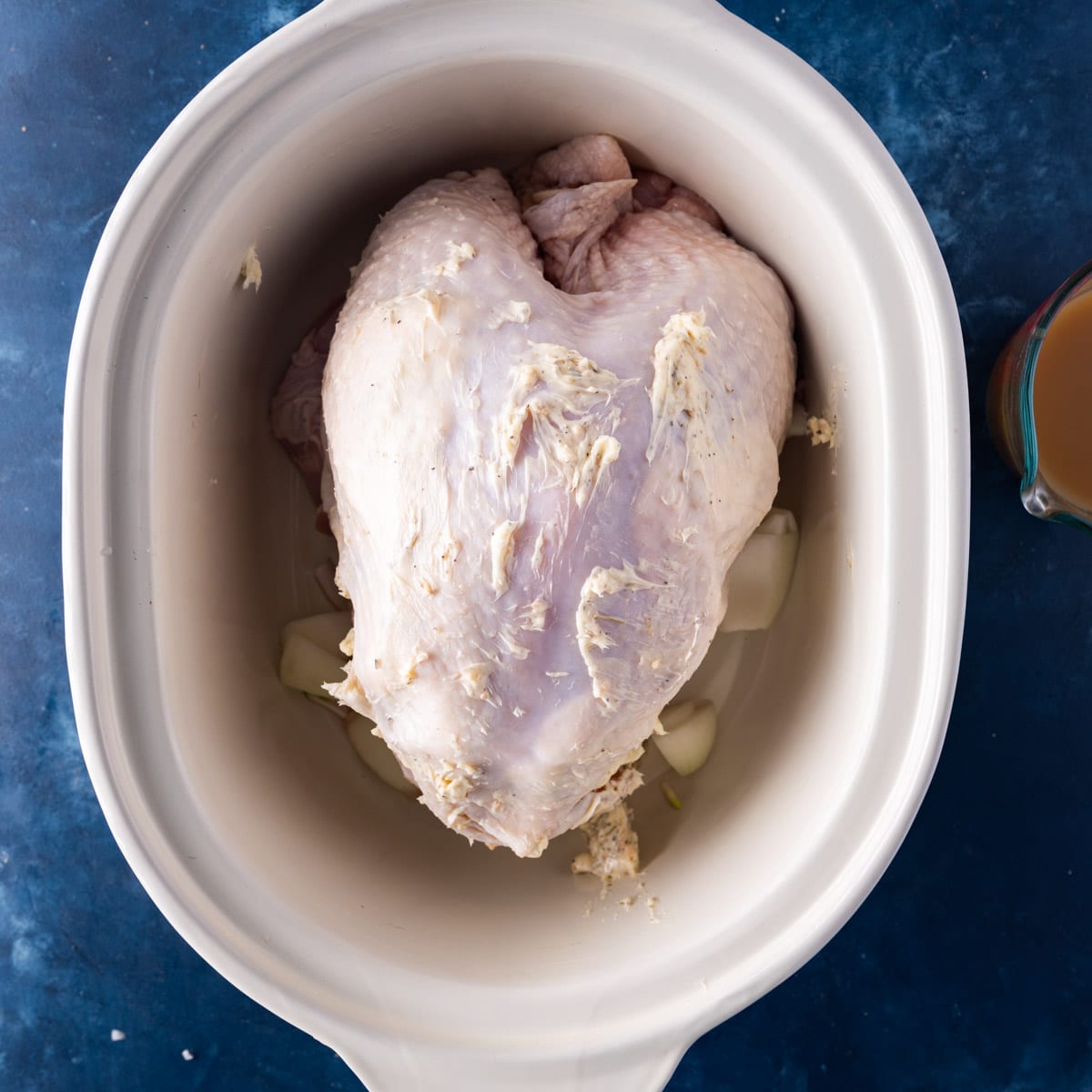 a turkey breast with butter on top in a crockpot