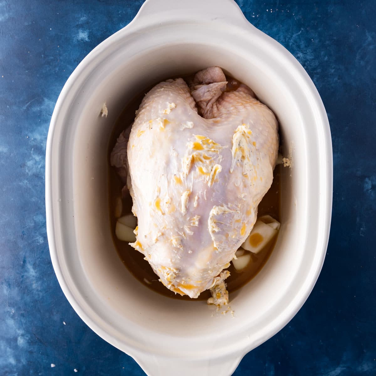 a turkey breast with butter and orange juice on top in a crockpot