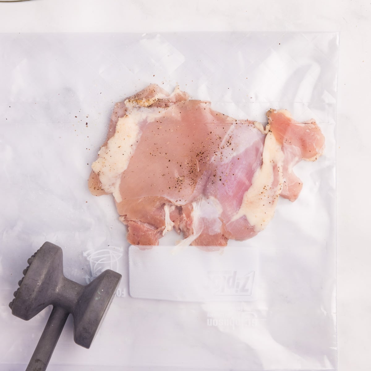 raw chicken in a bag pounded flat