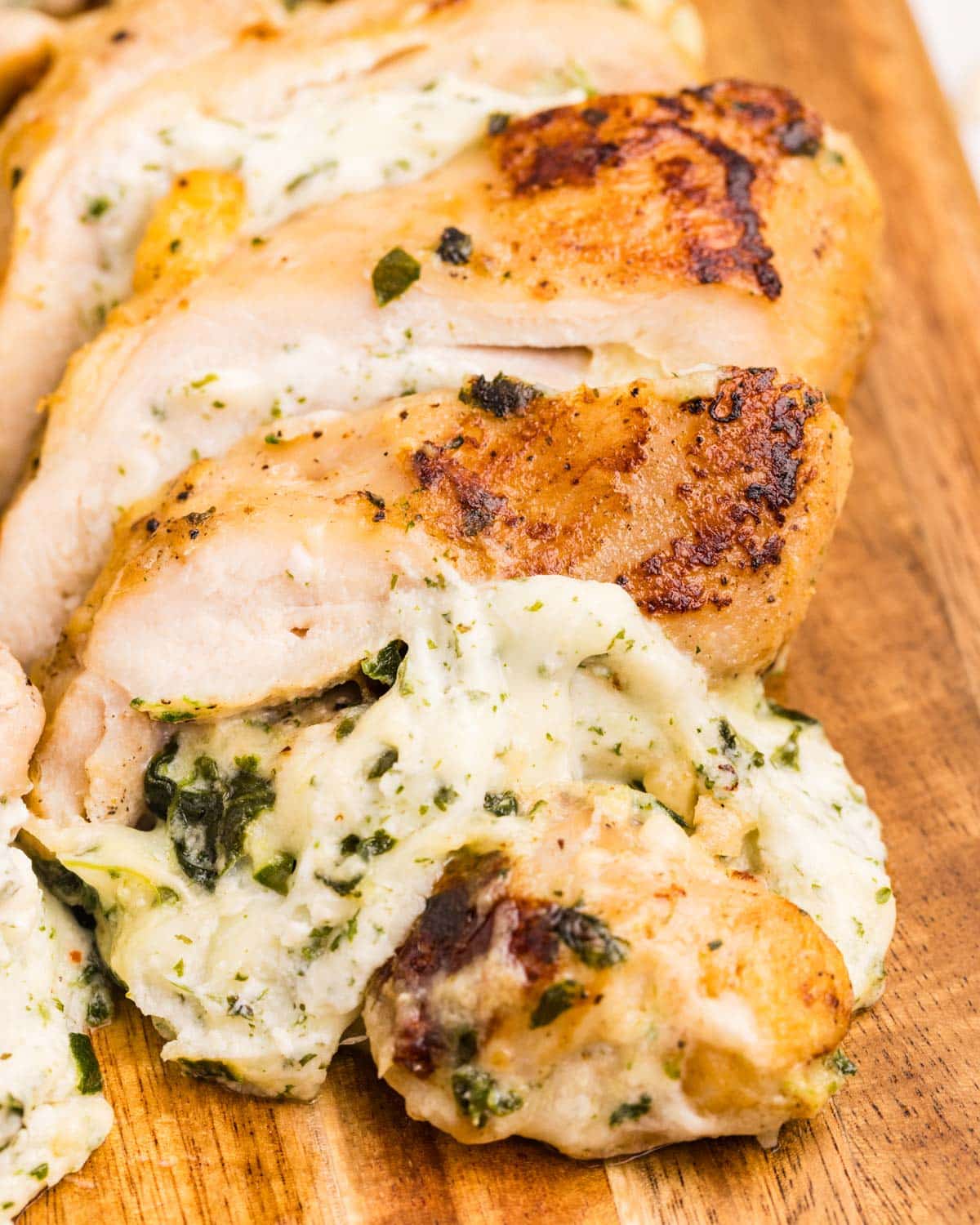 a sliced chicken thigh stuffed with spinach and cheese on a cutting board