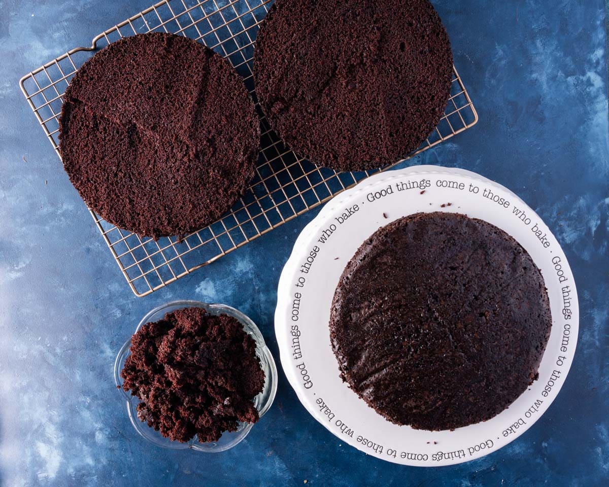 cakes sliced in half on a table, one bowl of cake crumbs