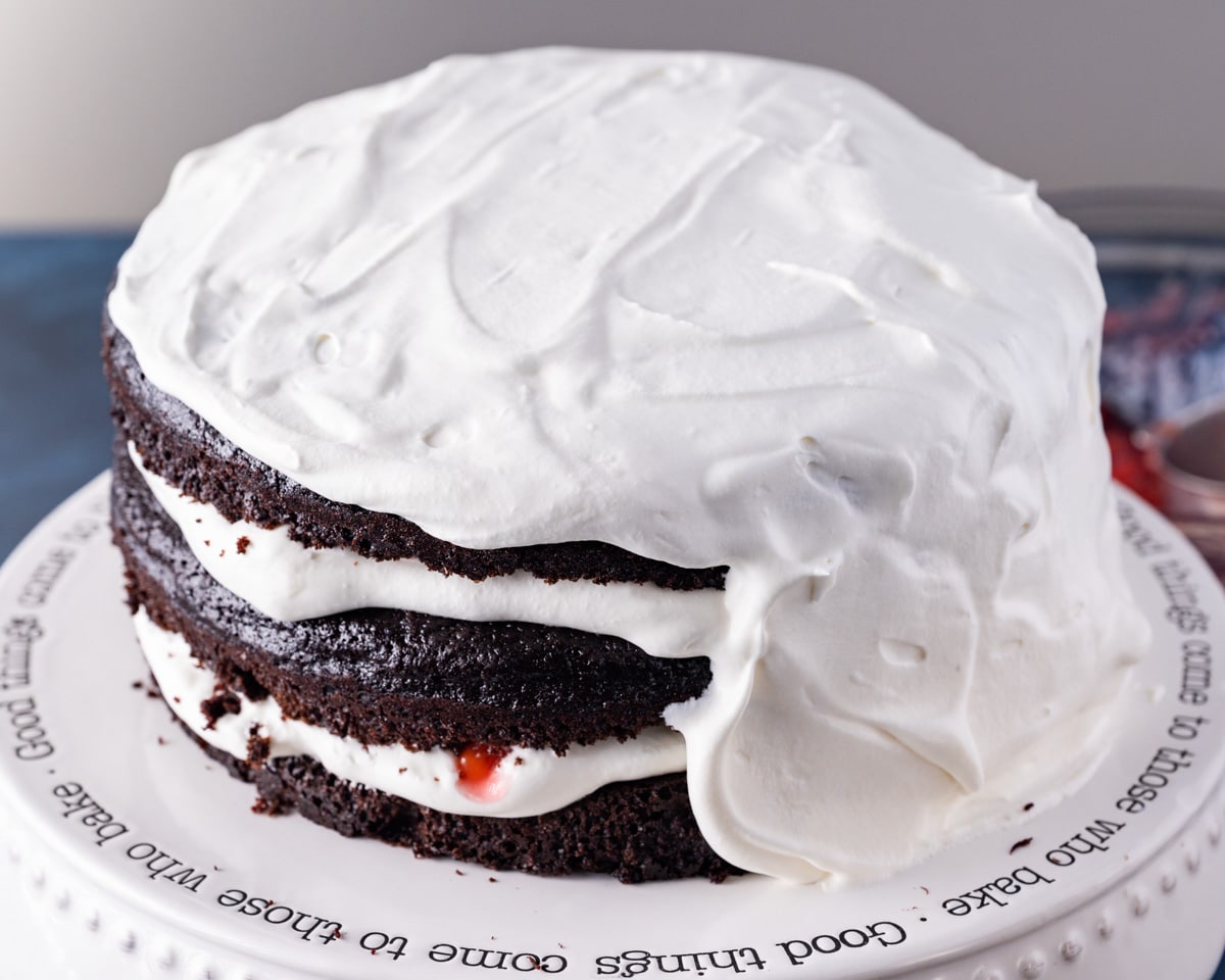 a cake half frosted with whipped cream