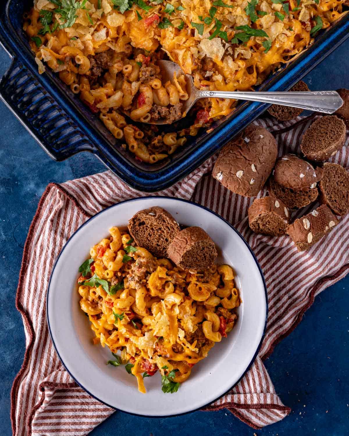 hamburger macaroni casserole on a table with sliced bread