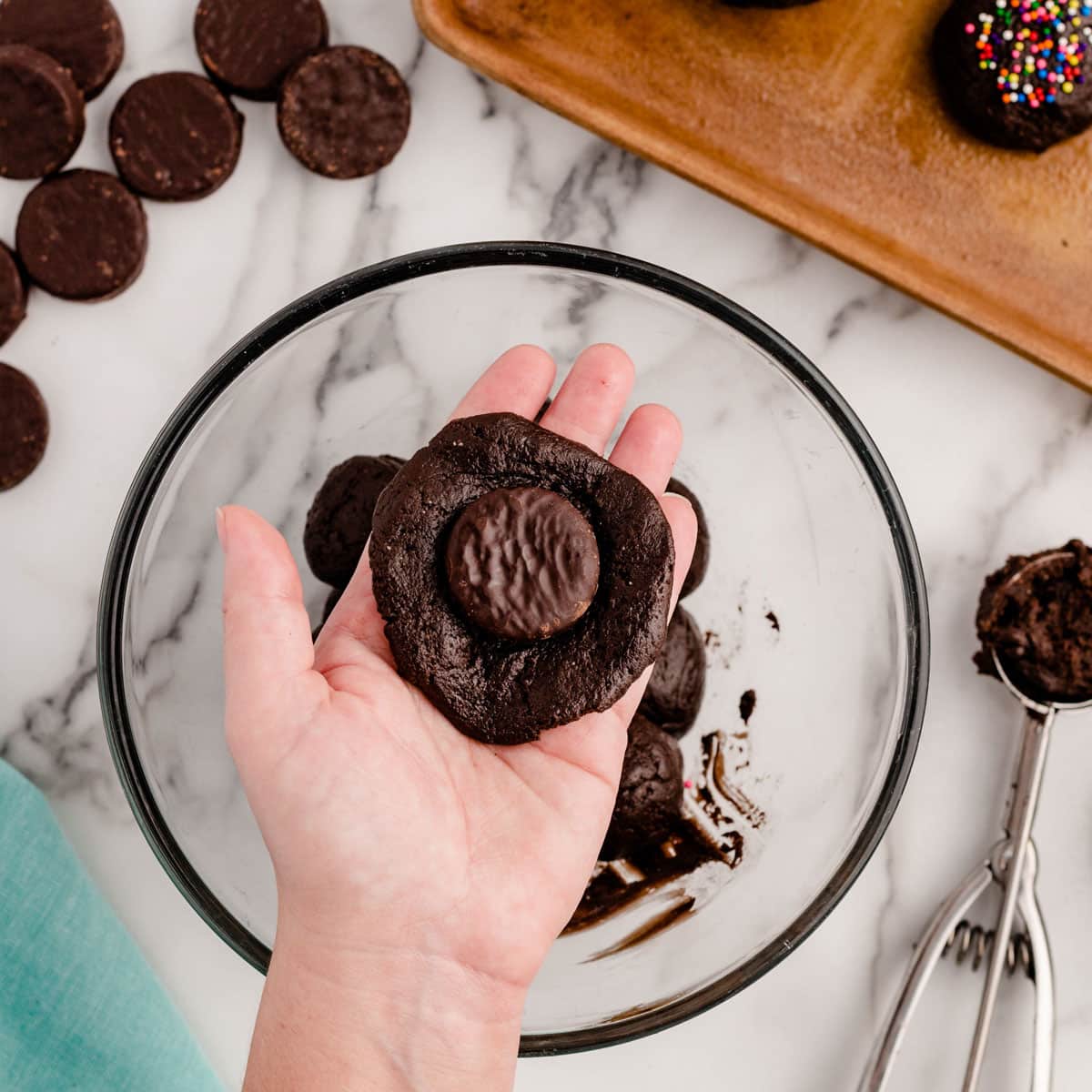 a hand holding cookie dough with a peppermint patty on top