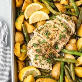 sliced chicken on a sheet pan with potatoes and green beans