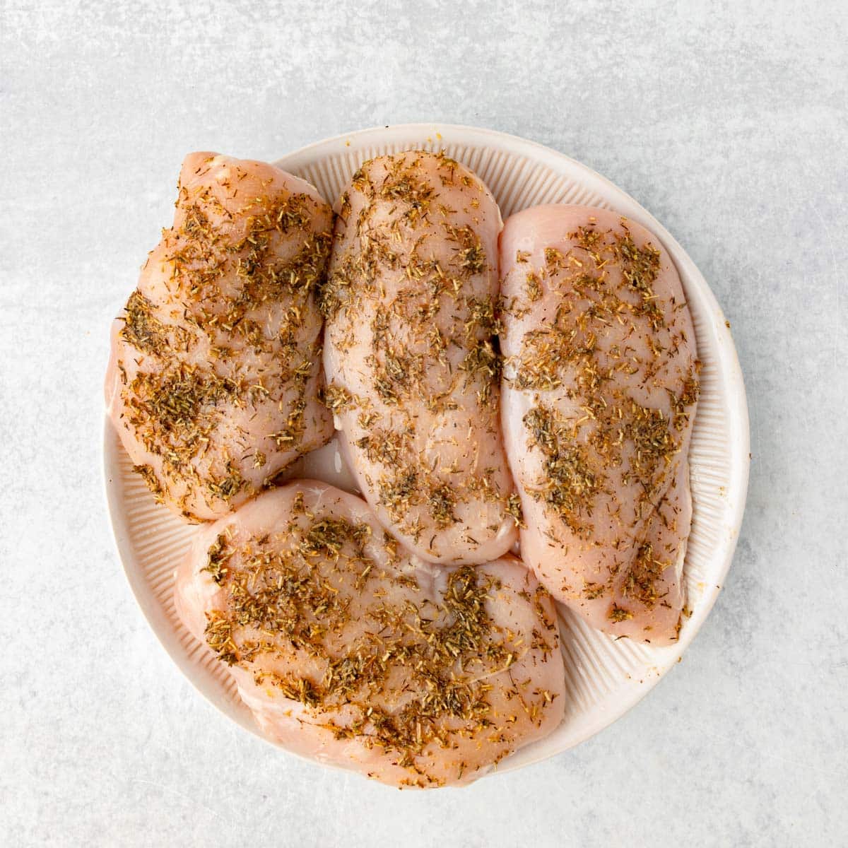 uncooked herbed chicken on a plate