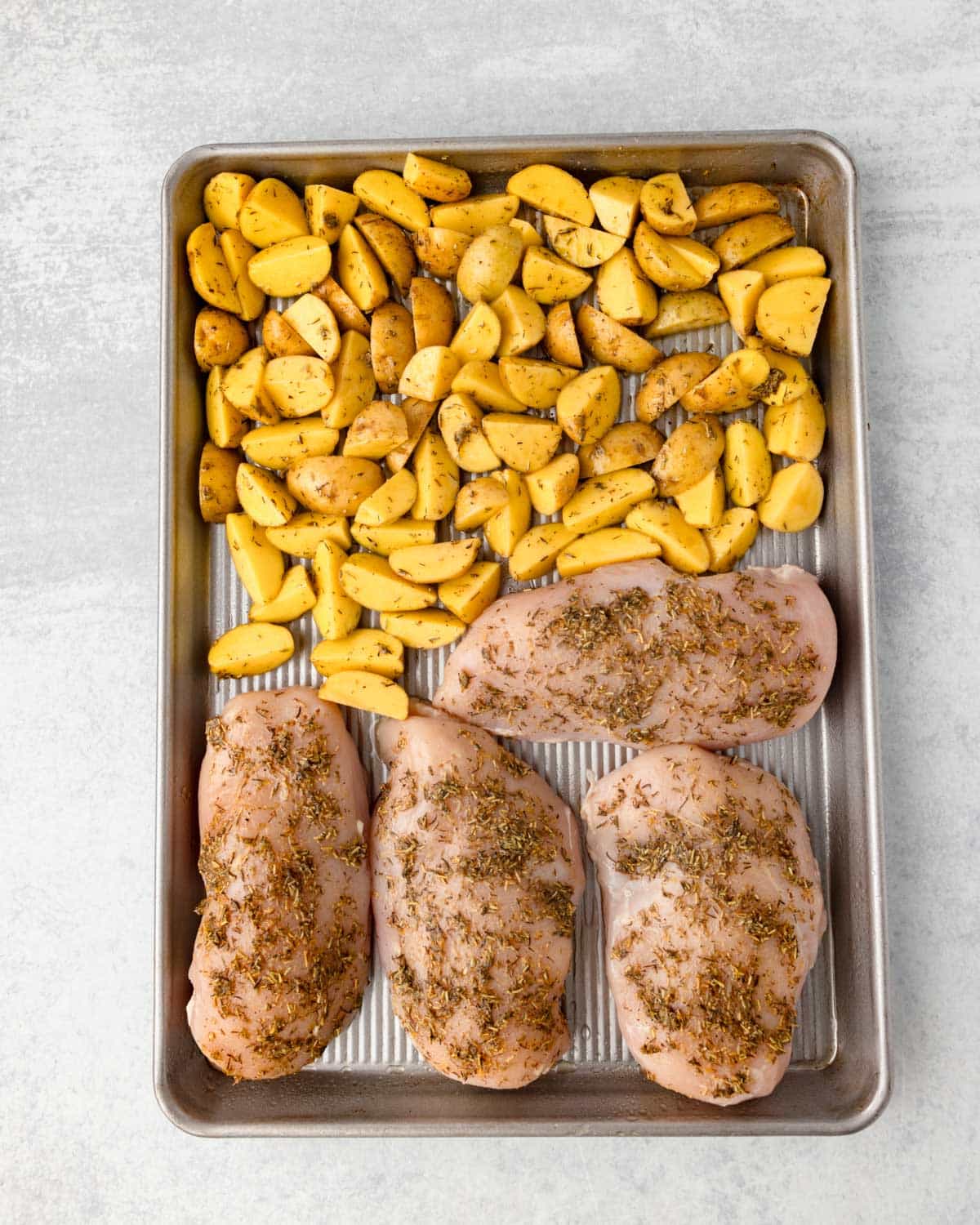 uncooked chicken and potatoes on a pan