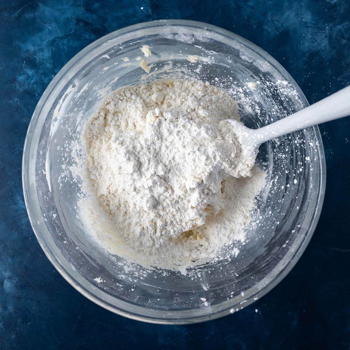 flour over creamed butter and sugar in a bowl