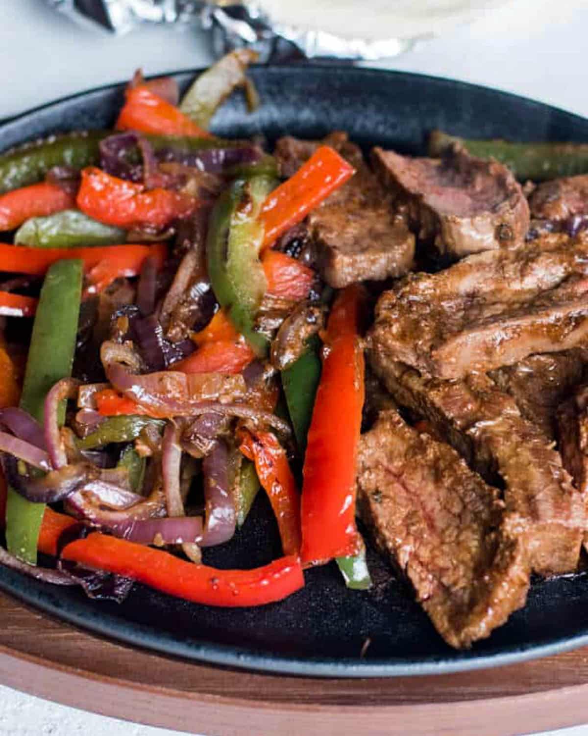 steak and peppers on a cast iron fajita pan