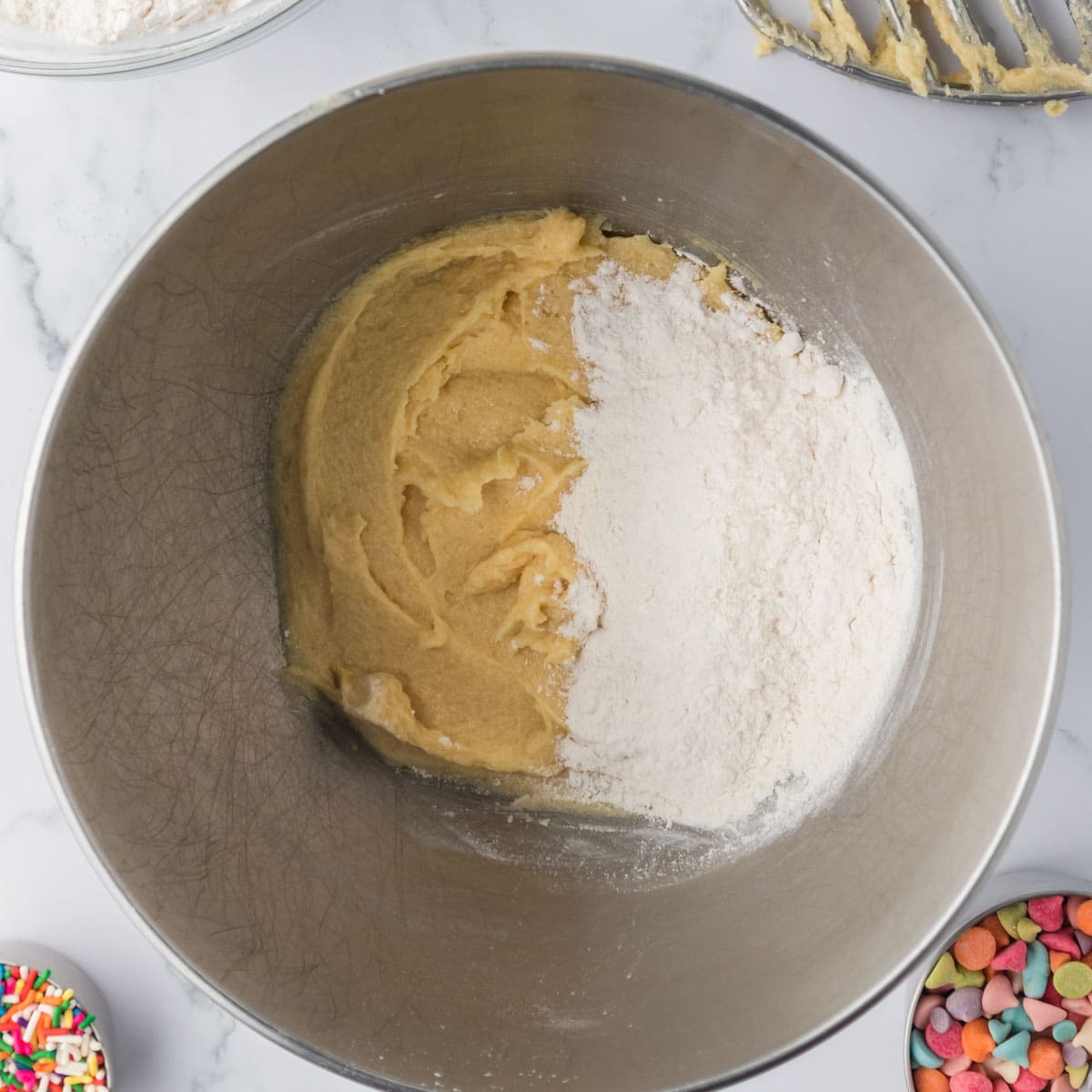 flour over cookie dough in a mixing bowl