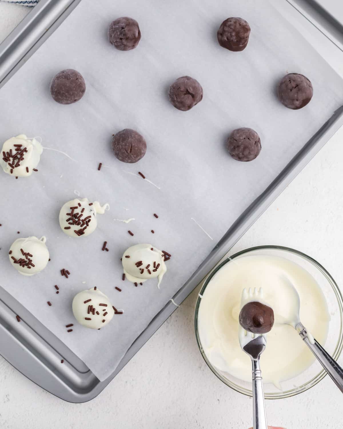 dipping frozen brownie balls into white chocolate