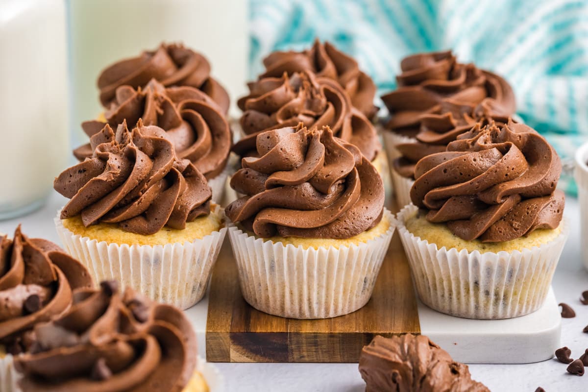 chocolate chip cupcakes with frosting on at able