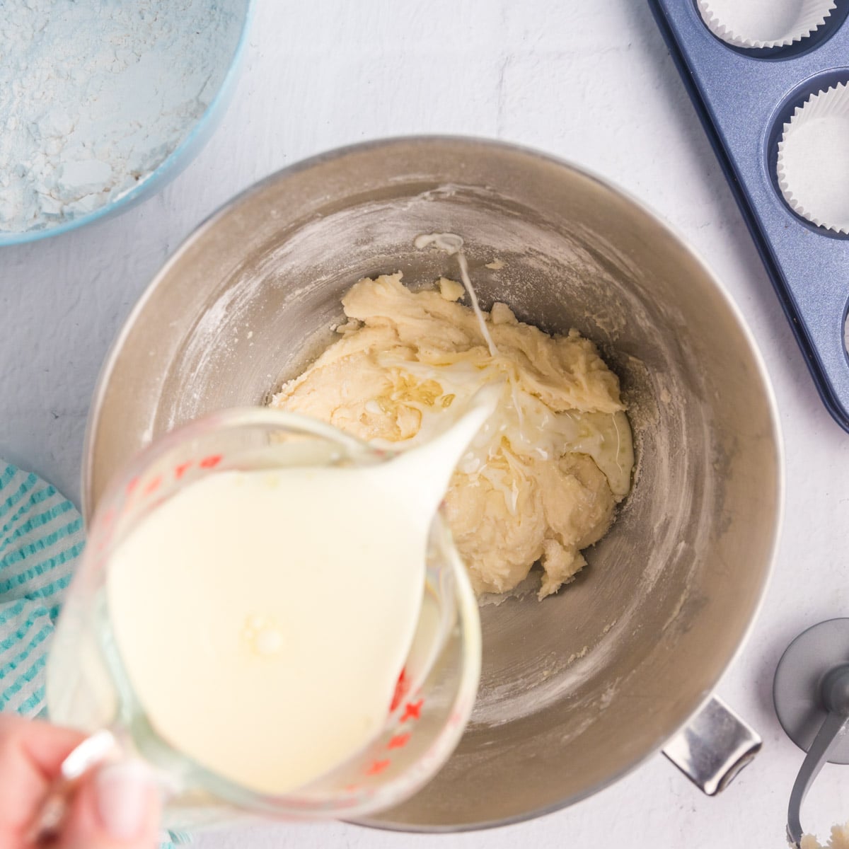 pouring milk into cake batter in a bowl