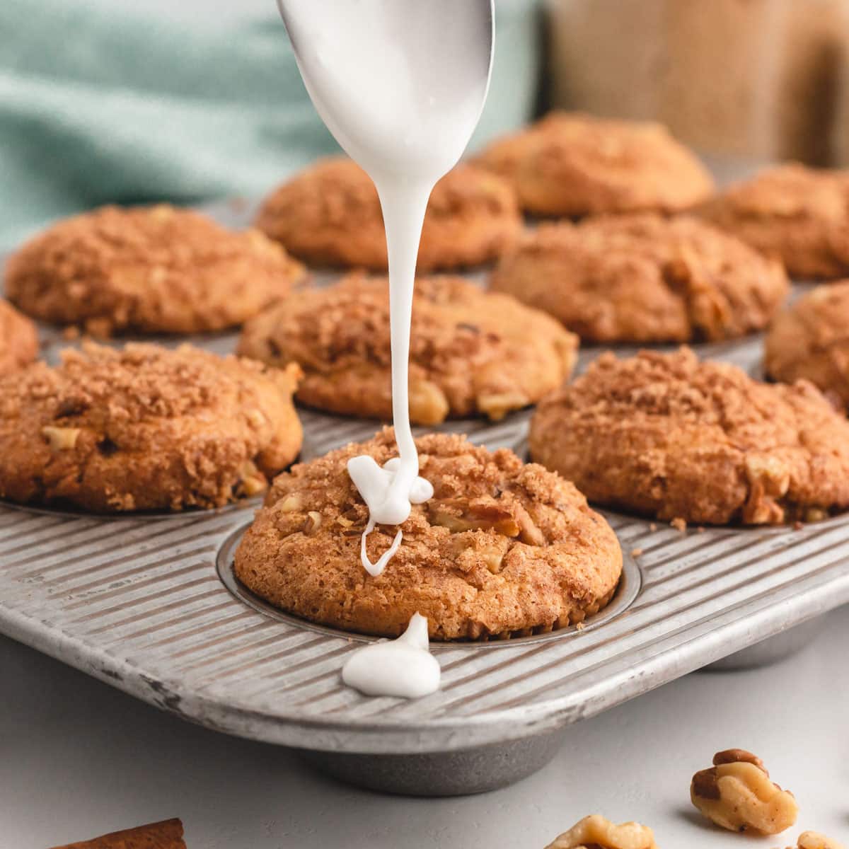 drizzling glaze over cinnamon pecan muffin