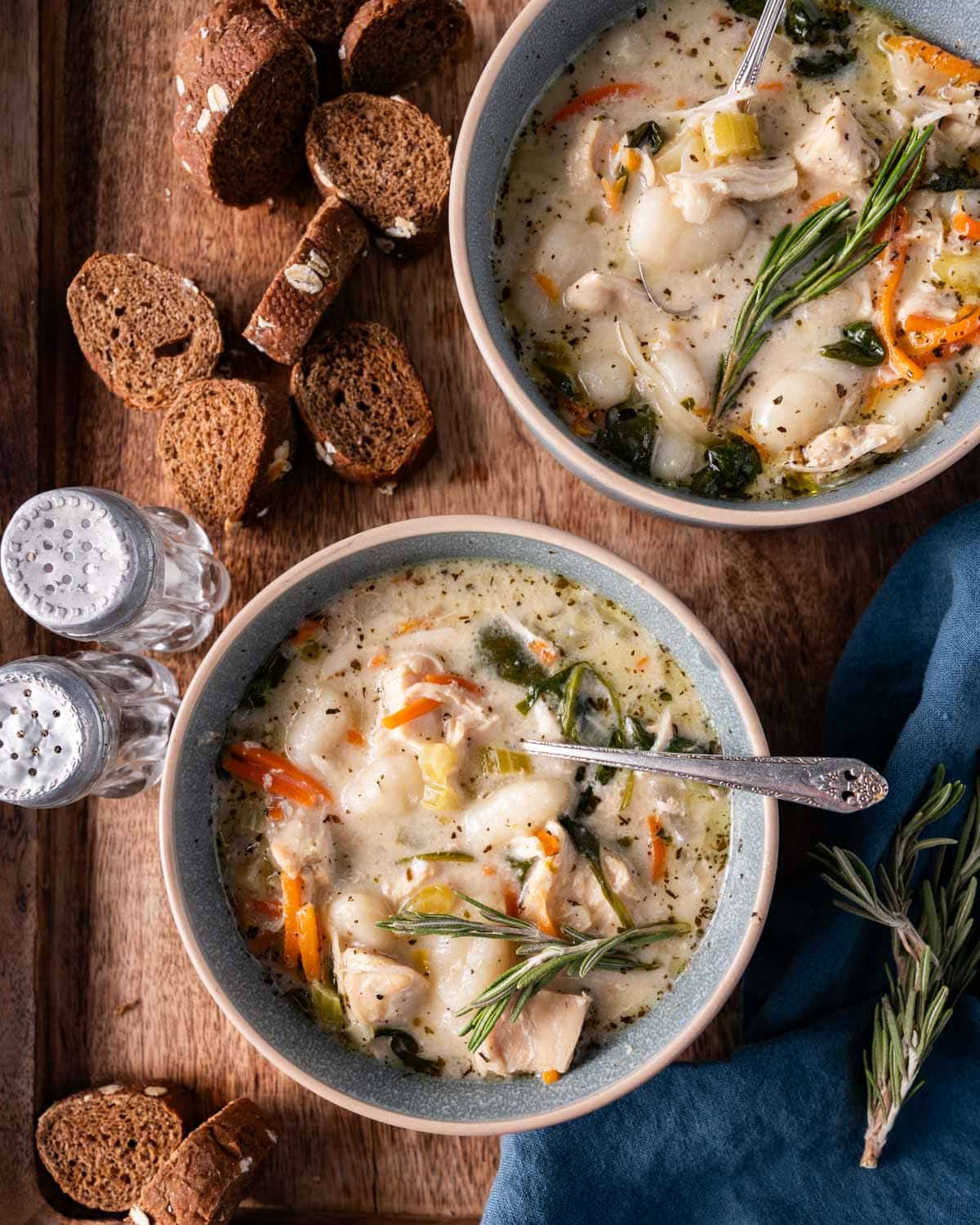 two bowls of chicken gnocchi soup with slices of bread